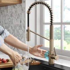 a woman is washing her hands under the kitchen faucet