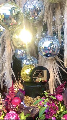 several disco balls hanging from a tree in front of some grass and flowers with the number four on it