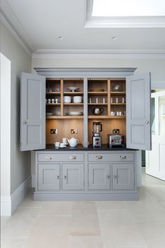 a kitchen with gray cabinets and white tile flooring on the walls, along with a skylight