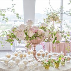 a table topped with lots of vases filled with flowers and desserts on top of it