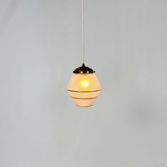 a white and black light hanging from a ceiling fixture on a gray wall in a room