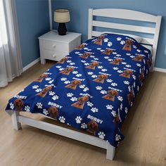 a bed in a bedroom with blue walls and wooden flooring has a dog print on it