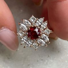 a woman's hand holding a red and white diamond ring