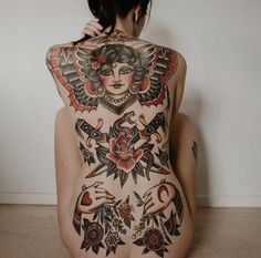 a woman sitting on the floor with tattoos on her back