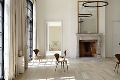 a living room filled with furniture and a fire place next to a window on top of a hard wood floor