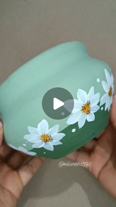 someone is holding a painted rock with daisies on it and the video appears to be playing