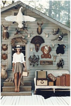 a woman standing in front of a house with deer heads on the wall and bags