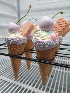 three ice cream cones with sprinkles are on a rack in the refrigerator