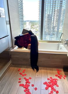 a woman with long black hair laying in a bathtub surrounded by red confetti