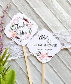 two wedding fans with flowers on them are sitting next to a potted plant and lace