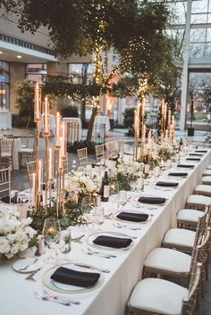 a long table is set up with white flowers and candles for an elegant wedding reception