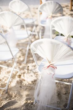 white chairs are set up in the sand for an outdoor wedding ceremony at the beach