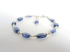 This handmade bracelet features lovely, genuine blue kyanite, the translucent ovals are varying sizes from 8x5.5 to 10.5x7mm (26.5cts total). They are spaced in a field of bright sterling silver...each stone is flanked by small, solid Bali style wheels with sparkly mirror-faceted beads in between. The bracelet is finished with 3 airy hammered links allowing the length to be adjustable at 7, 7.25 or 7.5 inches. The last link is decorated with a kyanite drop. This is a showy bracelet that can stan Adjustable Oval Sterling Silver Bracelet In Blue, Adjustable Oval Blue Sterling Silver Bracelet, Adjustable Blue Oval Sterling Silver Bracelet, Sparkly Mirror, Blue Multi-strand Bracelets With Gemstone Beads, Blue Multi-strand Gemstone Beads Bracelets, Elegant Blue Multi-stone Bracelet, Blue Multi-strand Handmade Beads, Blue Kyanite Round Bead Jewelry