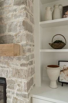 a stone fireplace in a living room with white shelves