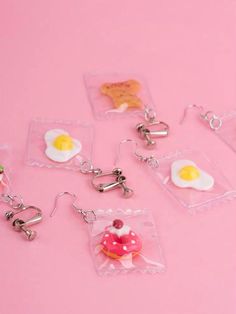 several keychains with different types of food in them on a pink table top