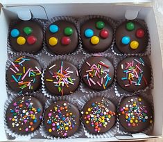 a box filled with chocolate cupcakes covered in sprinkles