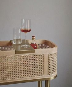 two wine glasses sitting on top of a wicker tray next to a bottle of wine