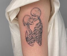 a woman's arm with a skeleton tattoo on it, holding the arm of another skeleton