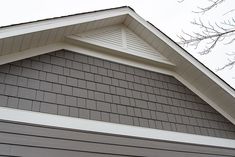 a bird is perched on top of the roof of a house that has gray shingles