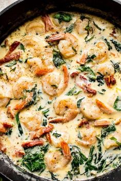 a skillet filled with shrimp, spinach and cheese