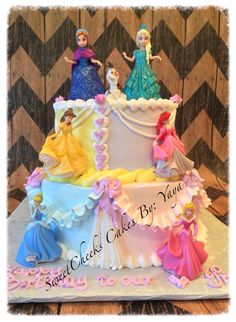 there is a large cake decorated with princesses on the top and bottom tiers