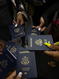 several people are holding their passports in one hand and pointing them at something on the other