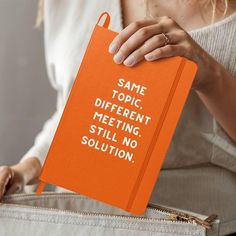 a woman holding an orange notebook that says same topic different meeting, still no solution