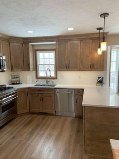 an empty kitchen with wood floors and white counter tops, is pictured in this image