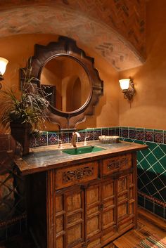 a bathroom with a sink, mirror and green tiled counter top in front of a wooden cabinet