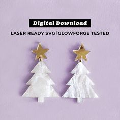 a pair of white and gold christmas tree earrings with stars on the top, against a purple background