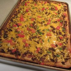 a square casserole with cheese and tomatoes on it