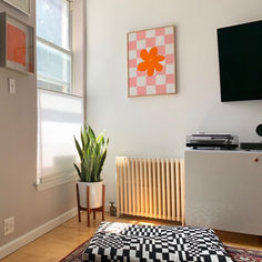 a living room with a couch, television and rugs on the hardwood flooring