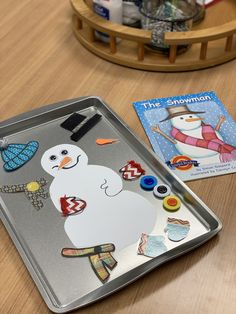 a tray with a snowman on it next to two children's coloring books