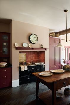 a kitchen with pink cabinets and an old fashioned stove in the center, along with a clock on the wall