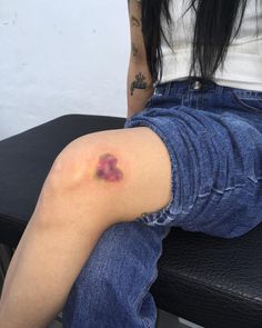 a woman sitting on top of a black chair with a tattoo on her arm and leg