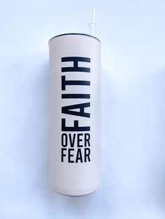 a white canister with the words faith over fear printed on it, sitting against a blue background