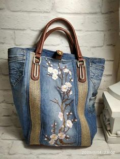 a blue jean purse with flowers painted on it