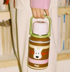 a person holding a brown and white bottle with a bear on it