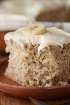 a close up of a banana cake on a plate with frosting and sliced bananas