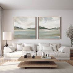 two paintings hang on the wall above a couch in a living room with white furniture