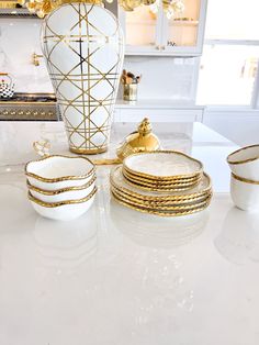 a white table topped with plates and vase filled with gold foiled flowers on top of it