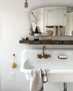 a white sink sitting under a bathroom mirror next to a wall mounted faucet