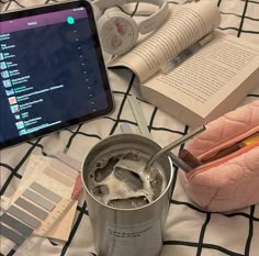 an open laptop computer sitting on top of a bed next to a can of paint