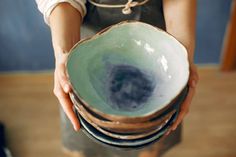 a person holding a stack of bowls in their hands