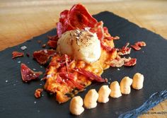 a black plate topped with food on top of a wooden table