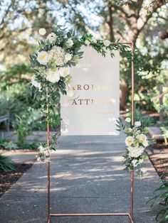 a sign with flowers and greenery on it