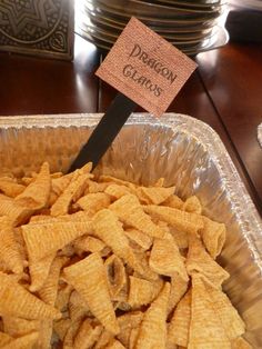 a container filled with cheetos sitting on top of a table next to plates