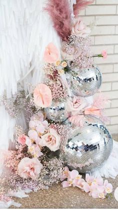 a silver vase filled with pink flowers next to a mirror ball and feather bouncy