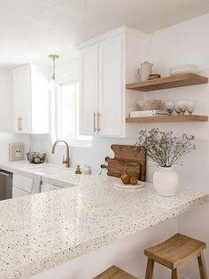 a white kitchen with marble counter tops and wooden stools