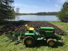 a green tractor parked next to a plowed field